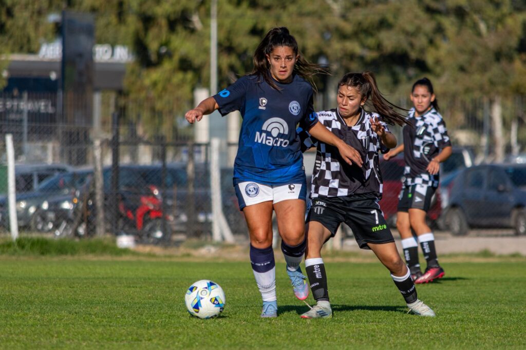 Dynamic action shot of female soccer players competing outdoors on a sunny day.