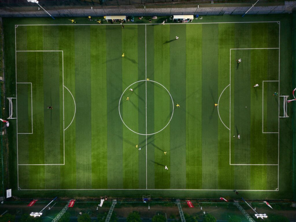 Dynamic aerial shot capturing a soccer match on a vibrant green field at night.