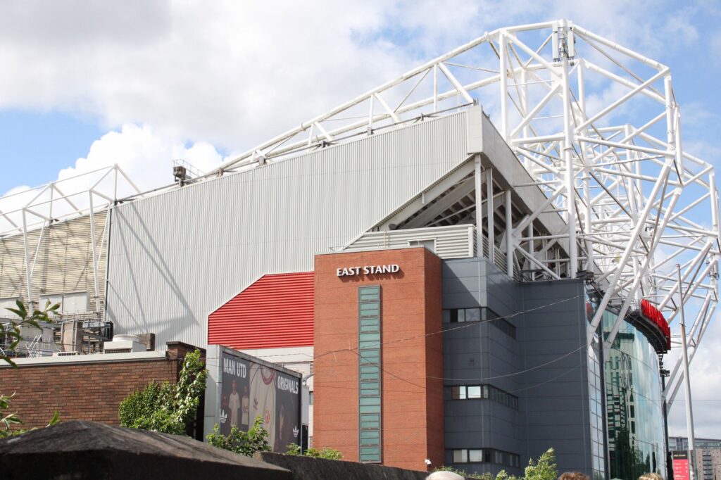 Exterior view of the East Stand at Old Trafford Stadium on a sunny day.
