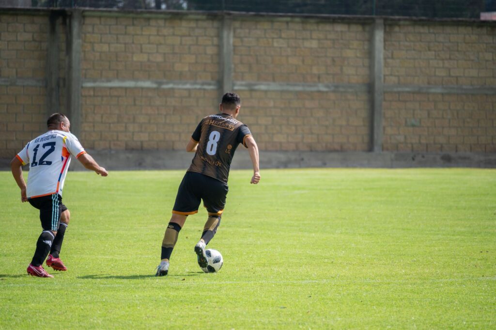 Two soccer players competing during a match on a sunny day in Texcoco, México.
