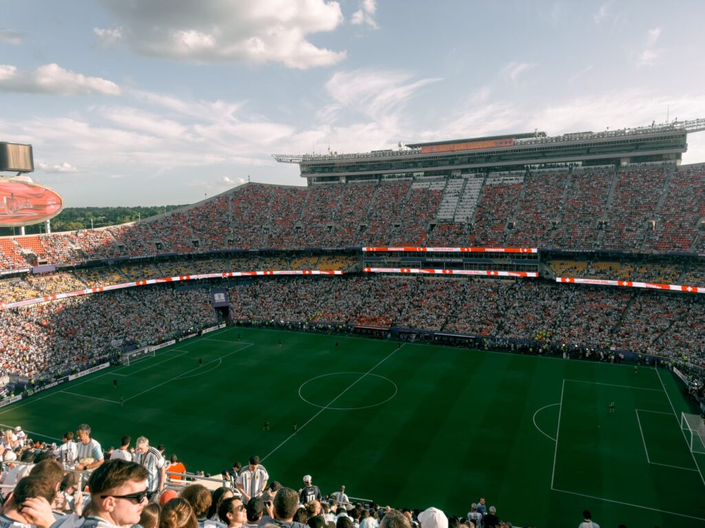 Aerial view of a lively soccer match in a bustling outdoor stadium filled with enthusiastic fans.