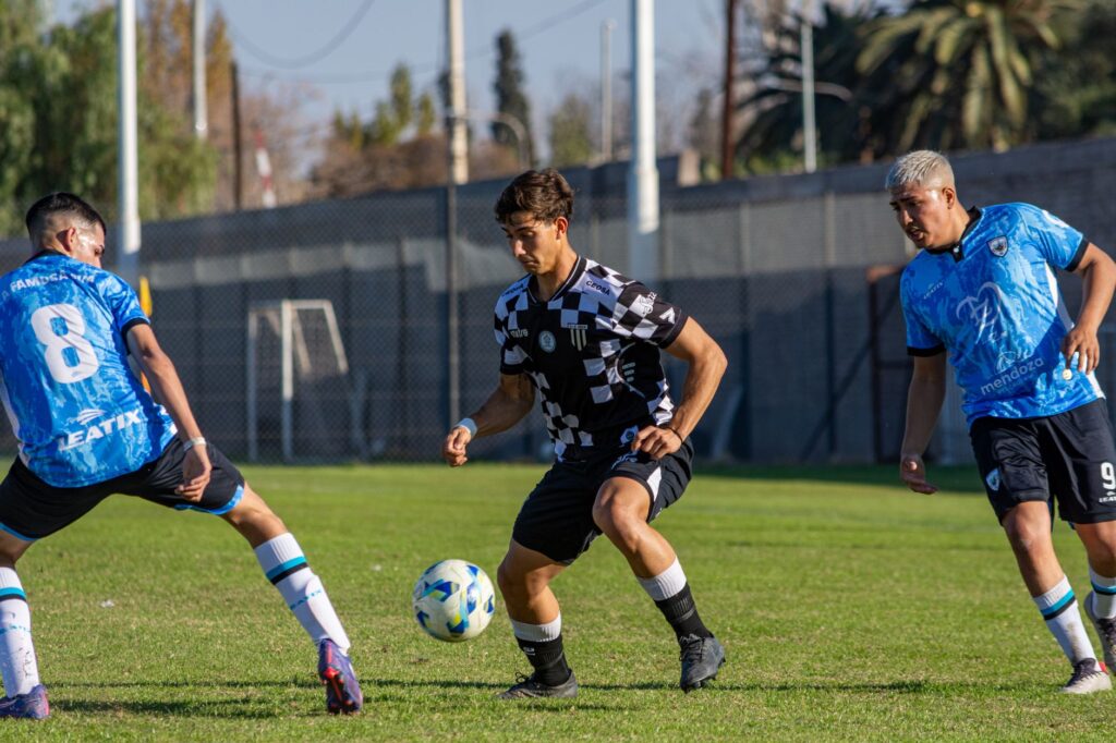 Three football players in action during a sunny outdoor match, showcasing athleticism and teamwork.