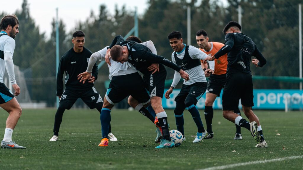 Intense soccer practice with team players competing for the ball on a green field.