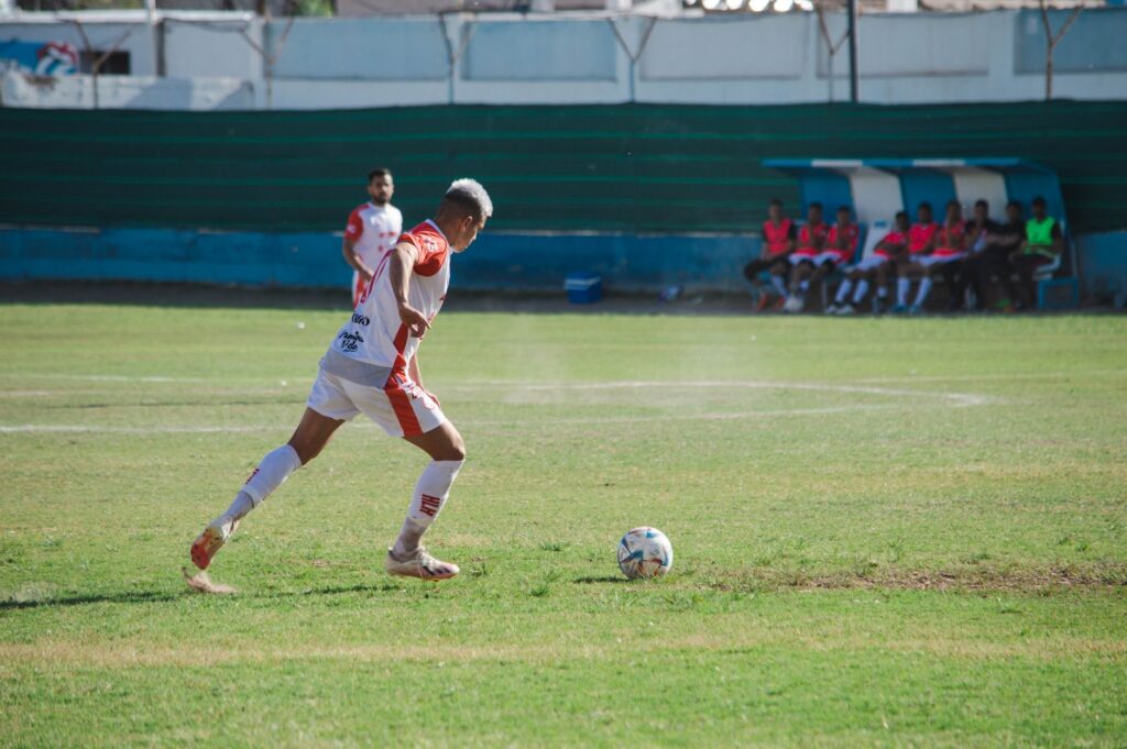 Male soccer player in action on the field during a sunny day match.