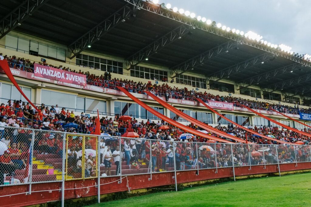 A vibrant stadium packed with passionate sports fans waving banners and cheering.